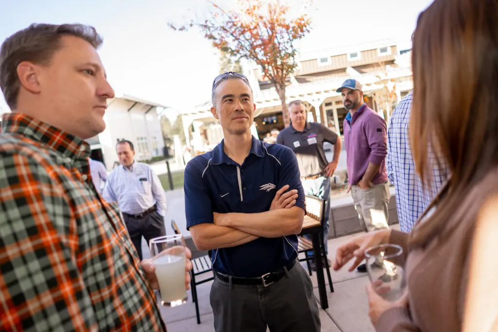 Professionals networking outside in conversation to build business leads and local connections